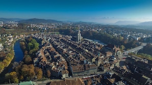 An aerial view of a historic city with a river, dense urban area, and a prominent tower.