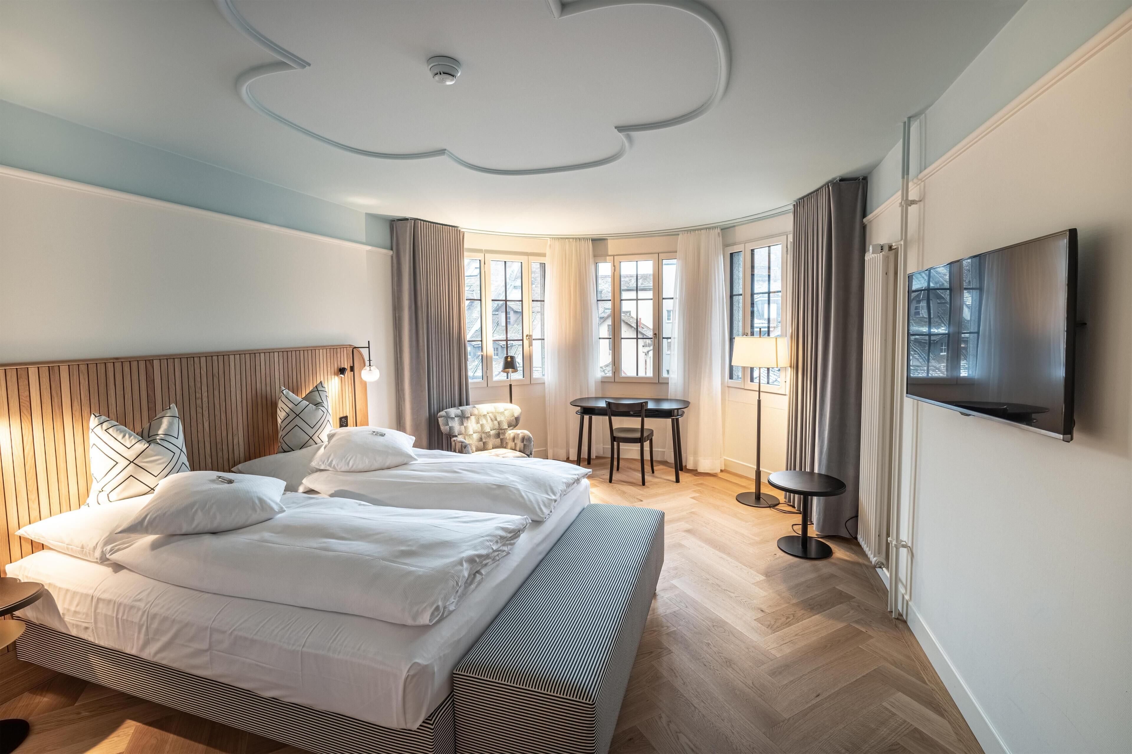 Ein Hotelzimmer mit einem großen Bett, einem Schreibtisch, einem Stuhl und einem Fernseher.