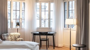 A hotel room with a bed, a chair, a table, and a lamp.