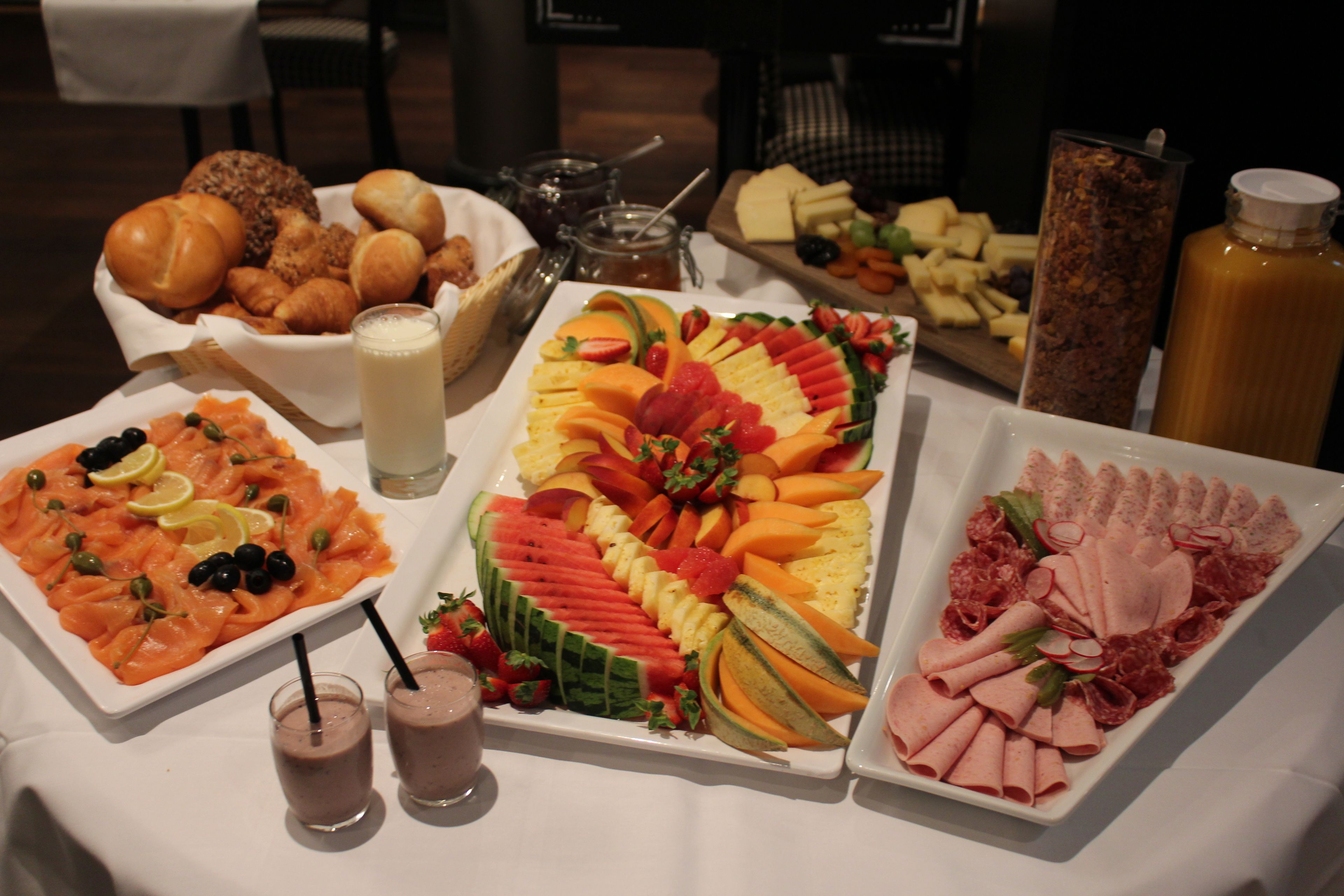 Un buffet proposant une variété de plats, notamment du saumon, des fruits et des fromages.