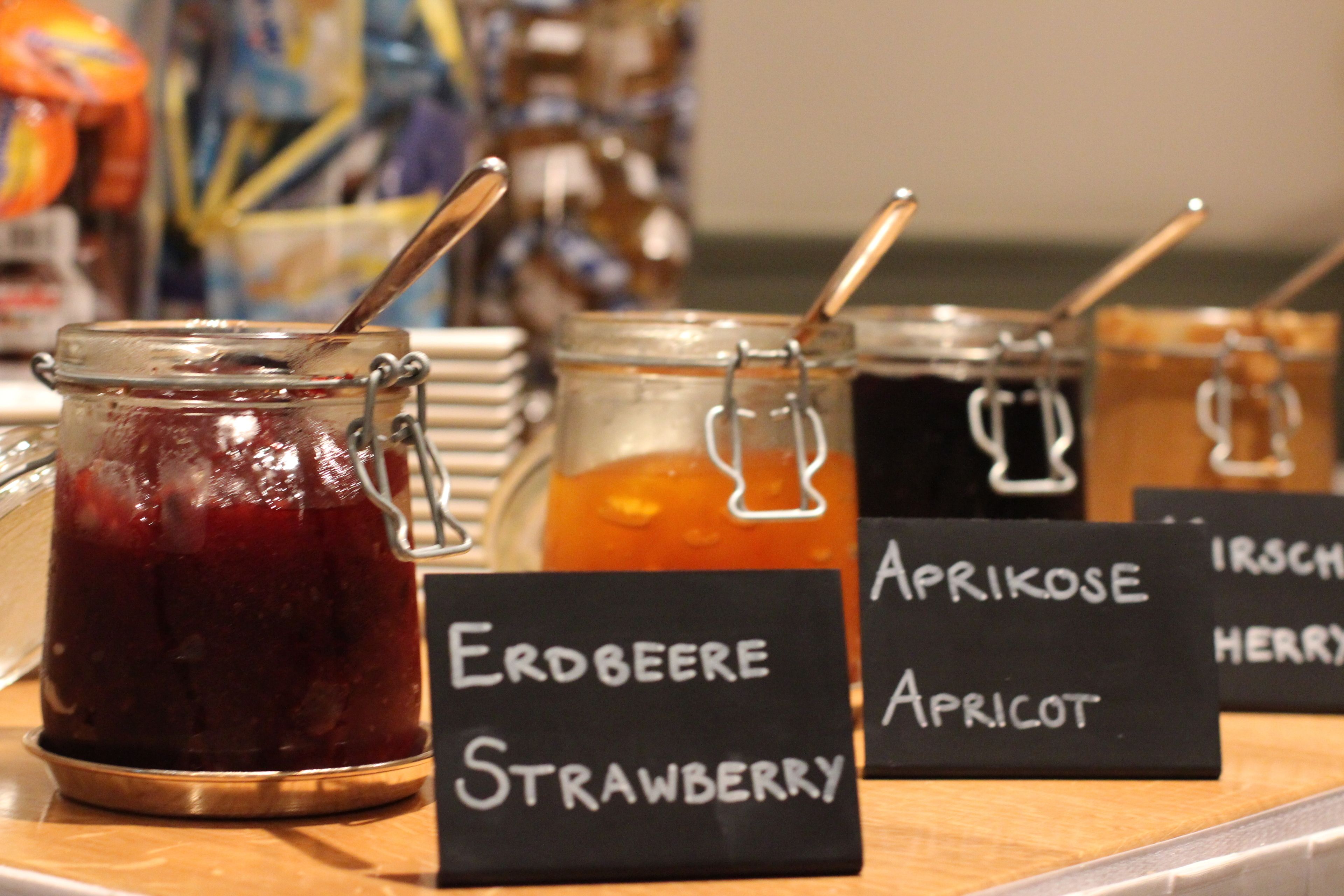 Jars of fruit preserves with labels indicating flavors like strawberry and apricot.