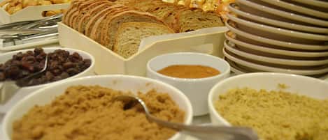 A buffet with various food items including bread, pastries, and condiments.