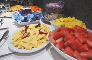 Una mesa de buffet con platos de fruta y vasos de parfait de yogur.