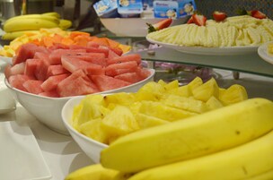 Un bufé con diversas frutas, como sandía, piña y plátanos.