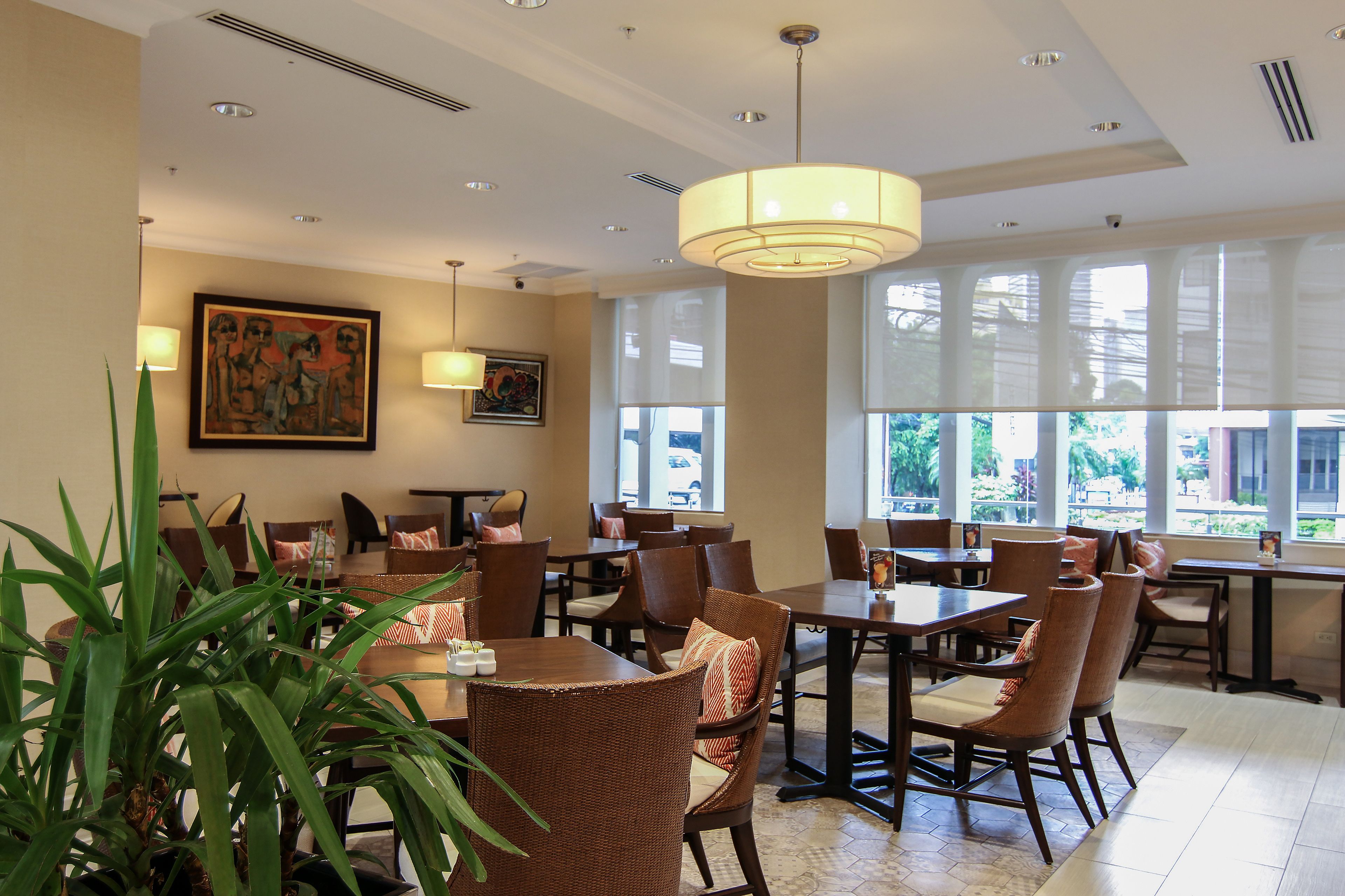 A restaurant with high ceilings, large windows, and wicker furniture.