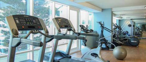 Un gimnasio con cintas de correr, elípticas y bicicletas estáticas.