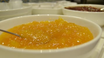 Ein Nahaufnahme einer Schüssel mit orangenem Fruchtkompott und einem Löffel.