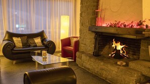 A modern living room with a stone fireplace, leather sofas, and a glass coffee table.