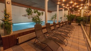 A pool area with lounge chairs, potted plants, and a view of the pool.