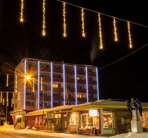 En byggnad med flera våningar, där det finns en restaurang på bottenvåningen, och som är upplyst av ljusslingor.