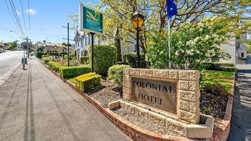 A Colonial Hotel sign with a brick border and a landscaped garden.