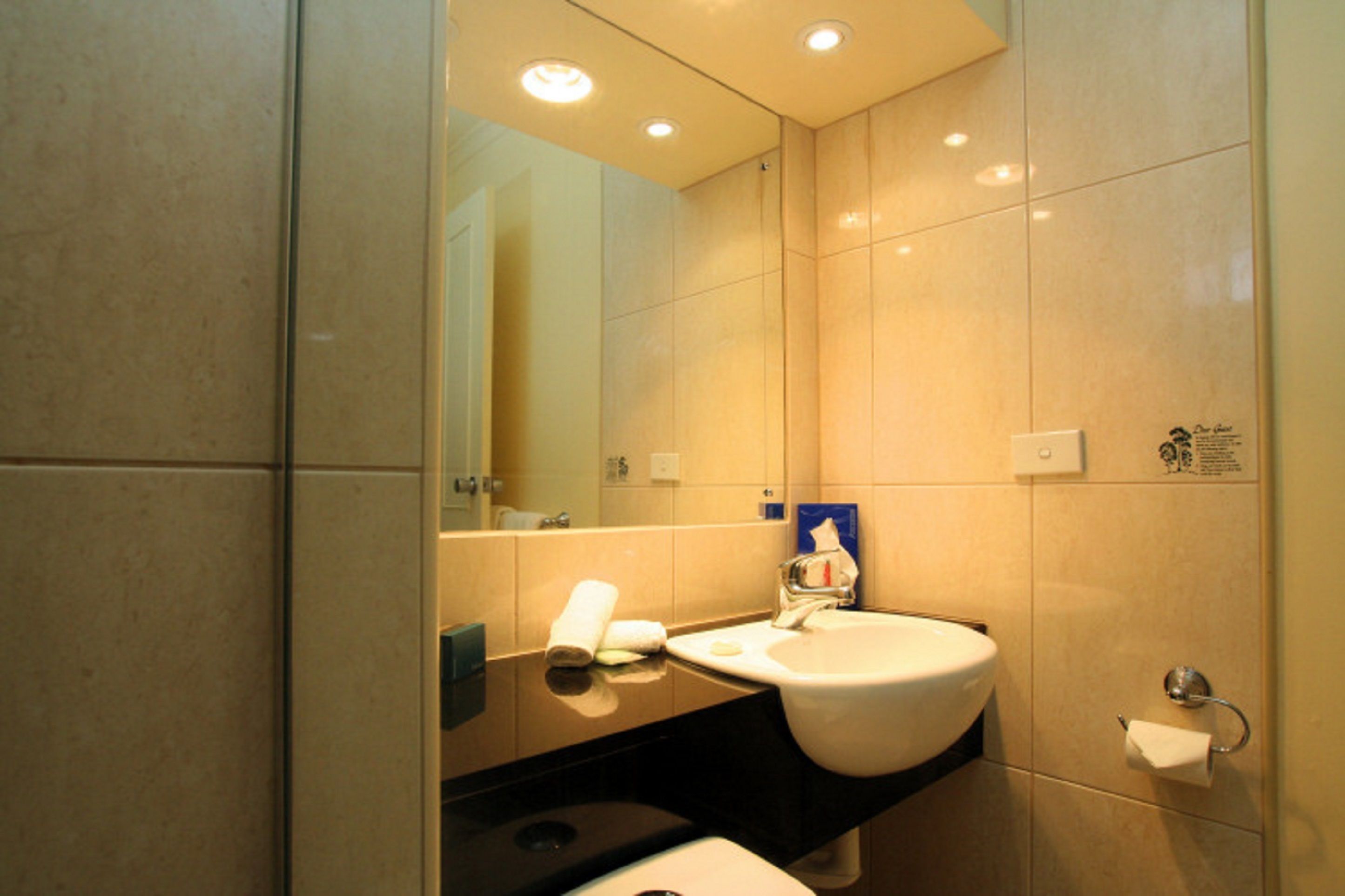 Une salle de bain moderne avec un grand miroir, un lavabo et des toilettes.
