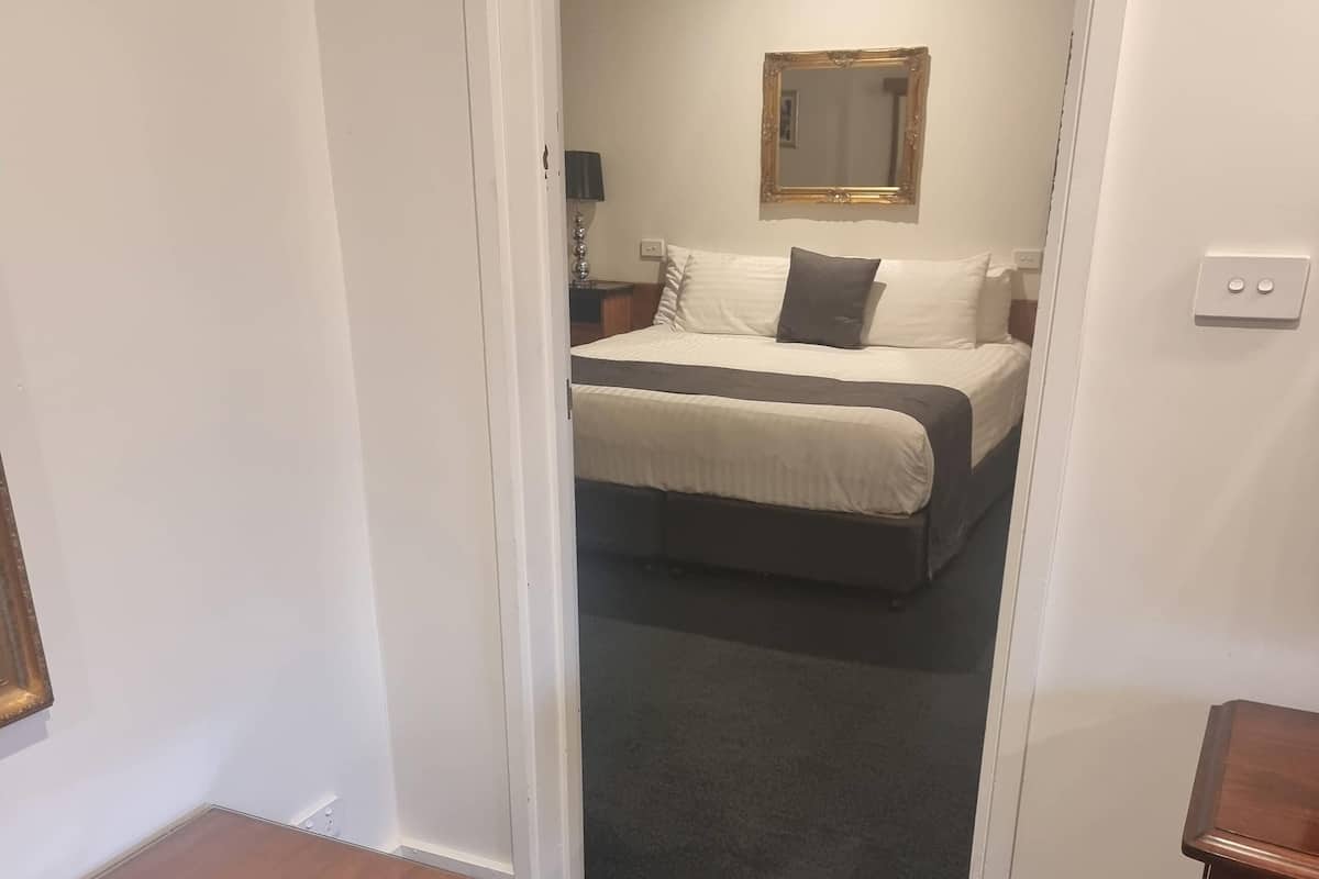 A hotel room with a bed, a nightstand, a lamp, and a mirror on the wall.