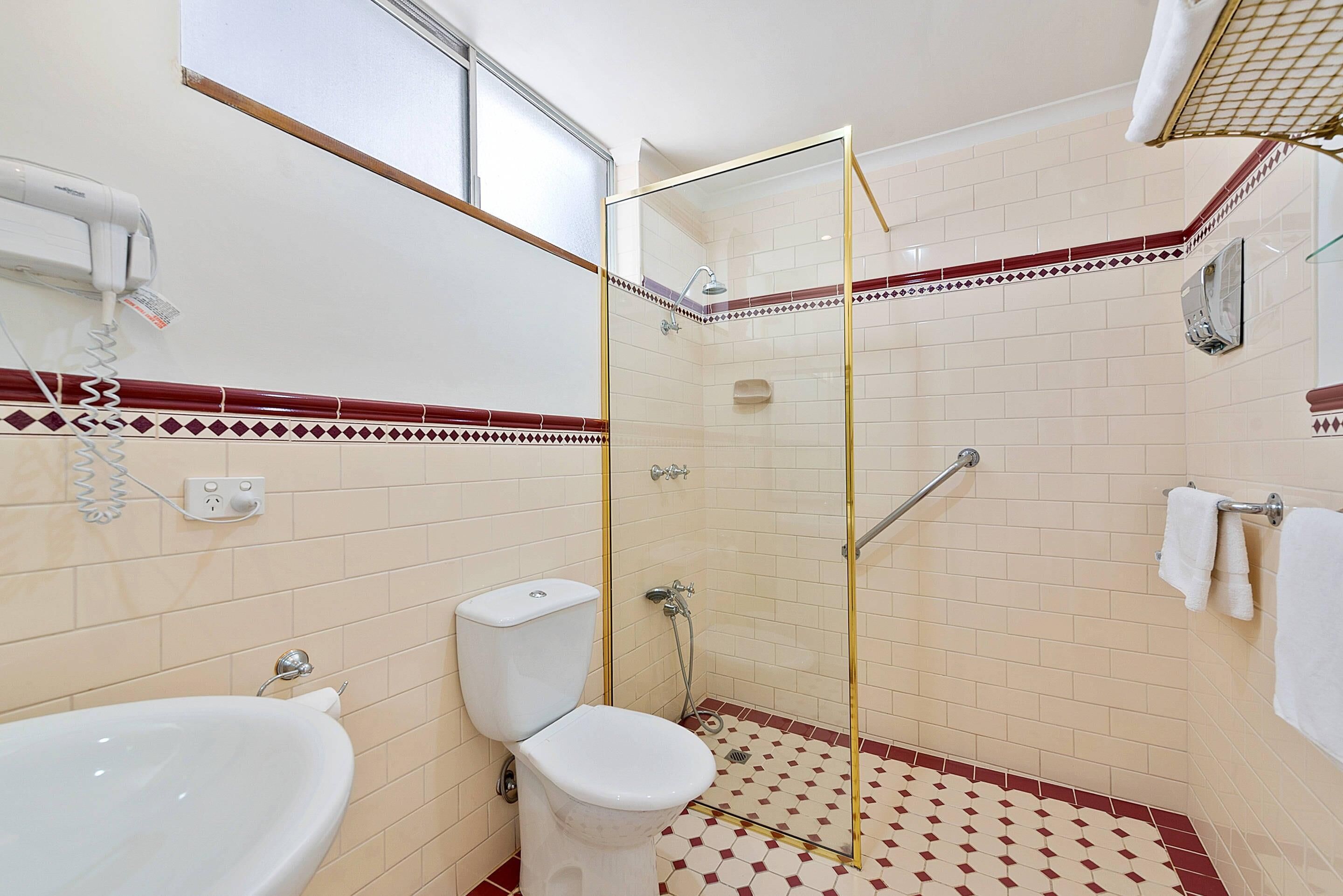 Een badkamer met een douche met glazen wand, een toilet en een wastafel.