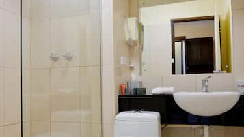 Un baño con ducha envuelta en vidrio, inodoro, lavabo y espejo.