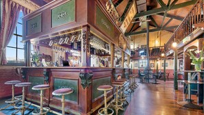 Una zona de bar con taburetes de madera, una barra y una escalera.