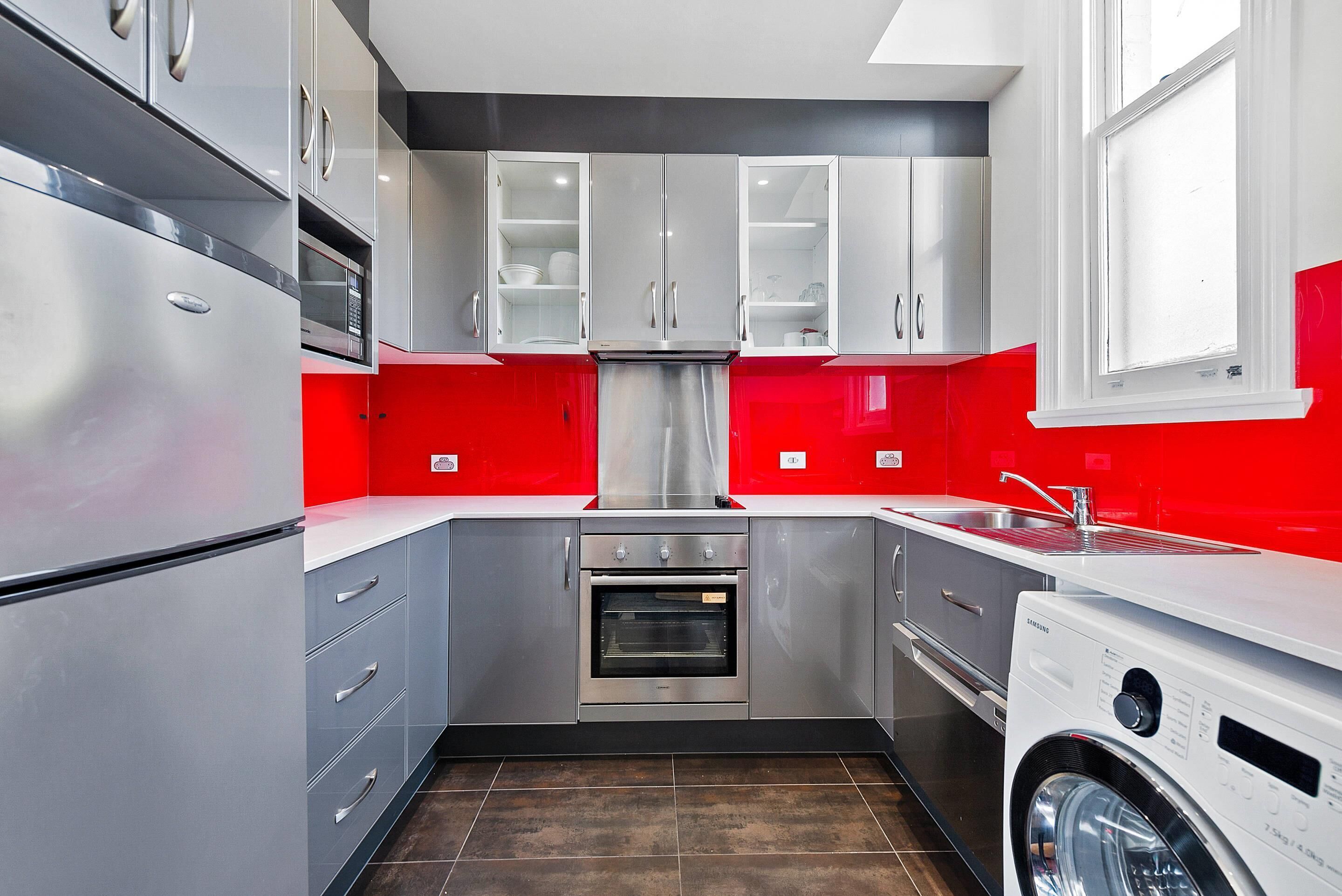 Una cocina compacta con electrodomésticos de acero inoxidable, horno integrado y lavadora.