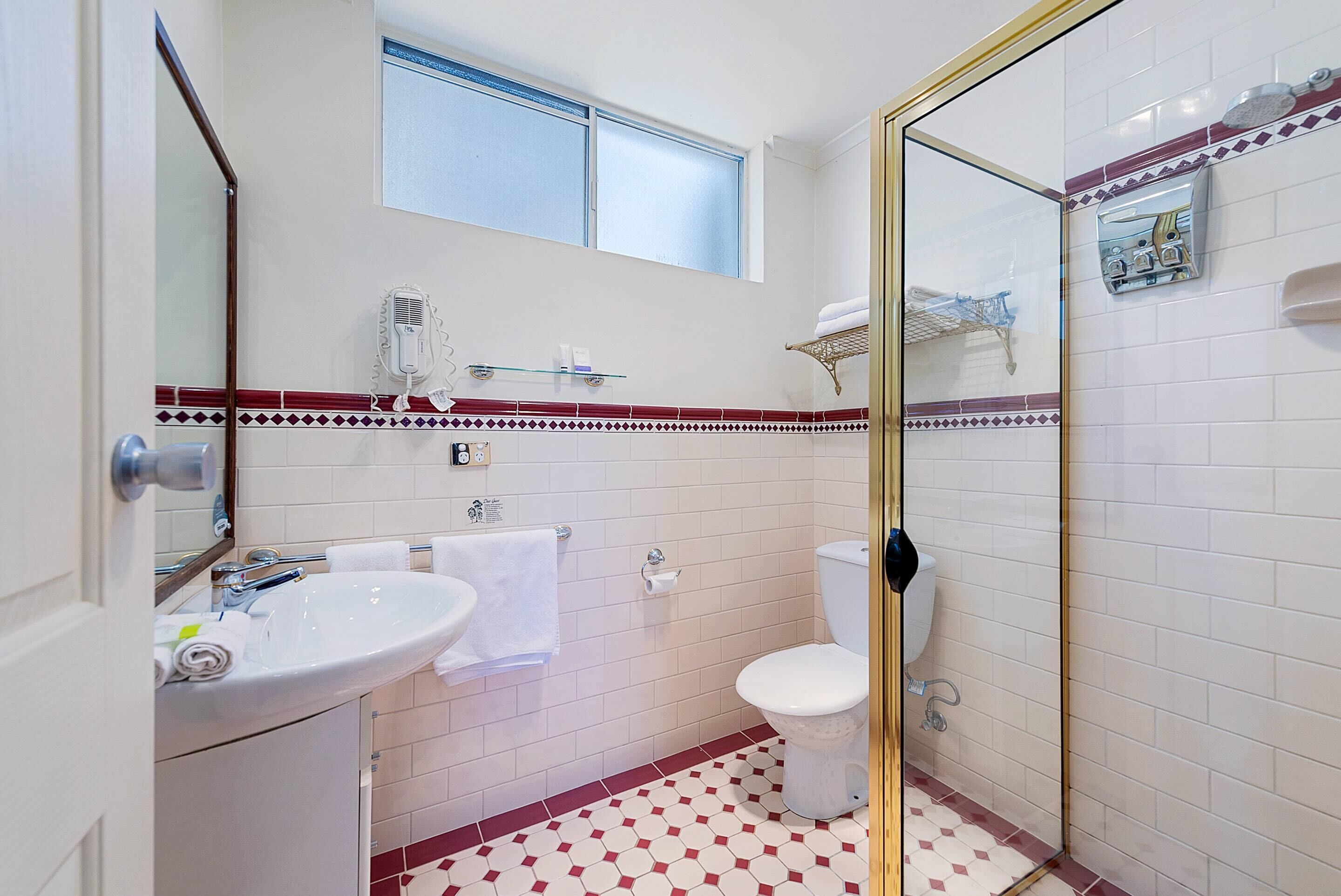 A bathroom with a white sink, toilet, and glass-enclosed shower.