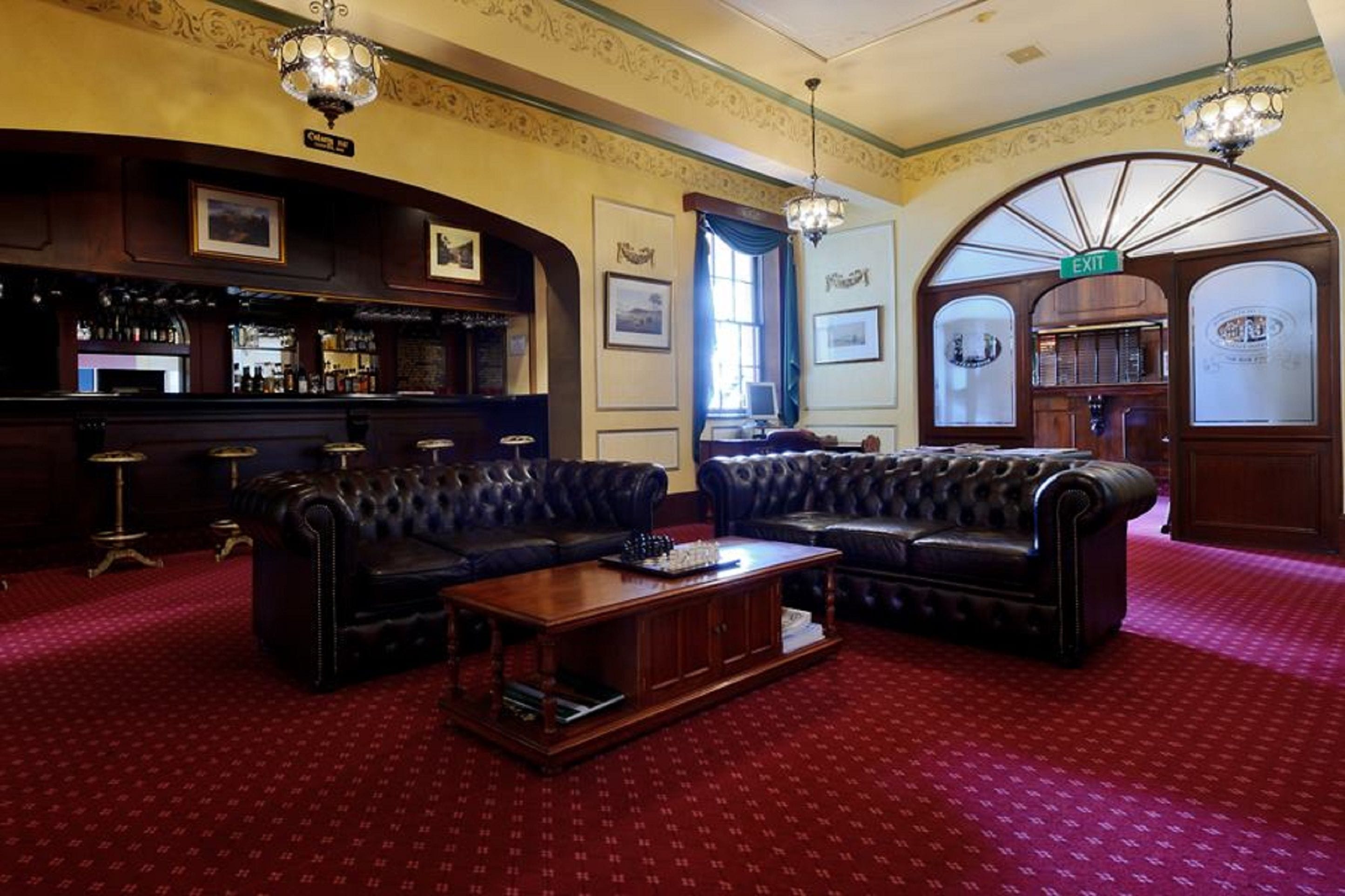 A bar area with leather sofas, a wooden coffee table, and a bar stocked with bottles.