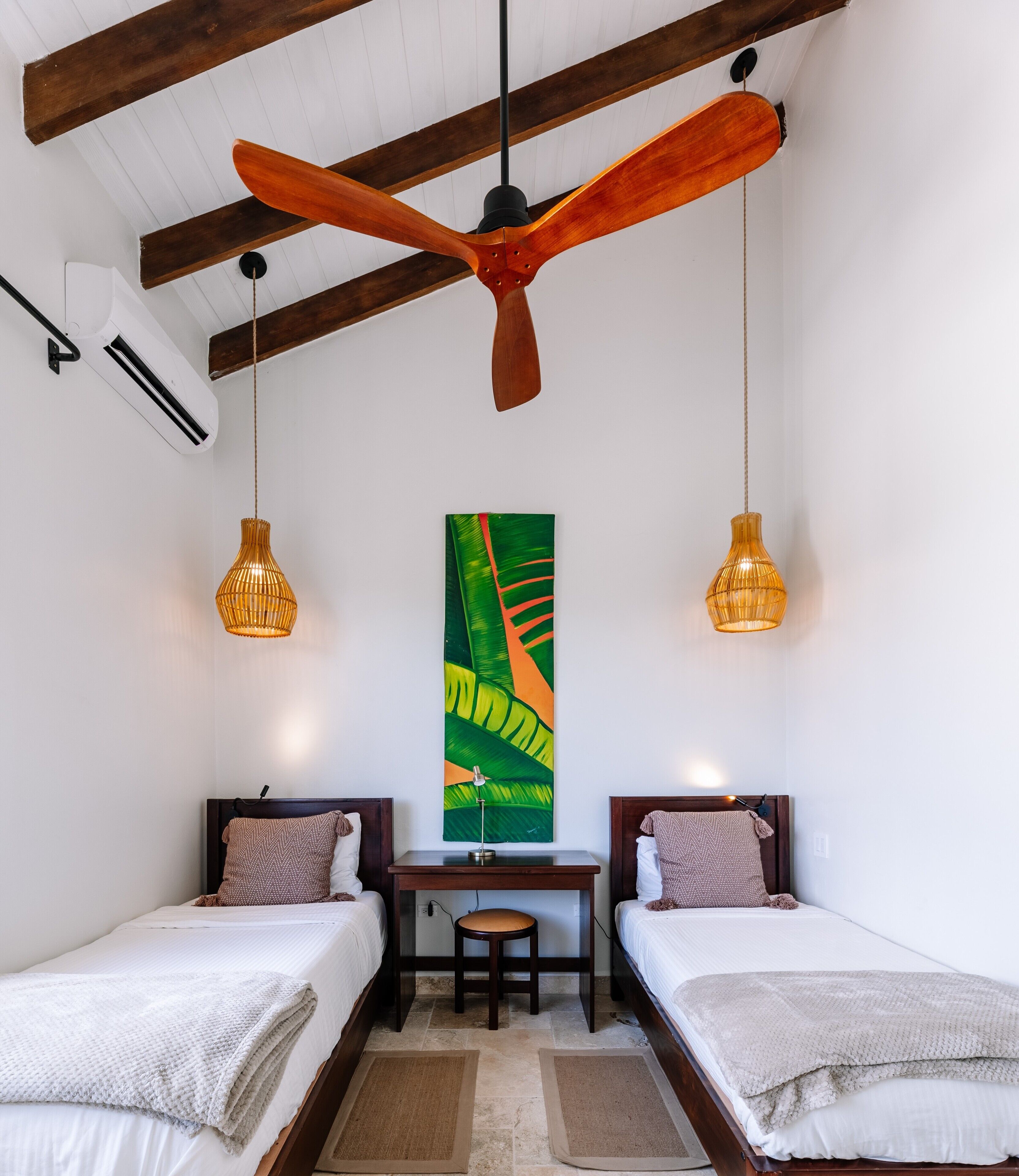 Una habitación con dos camas, un escritorio y un ventilador de techo.