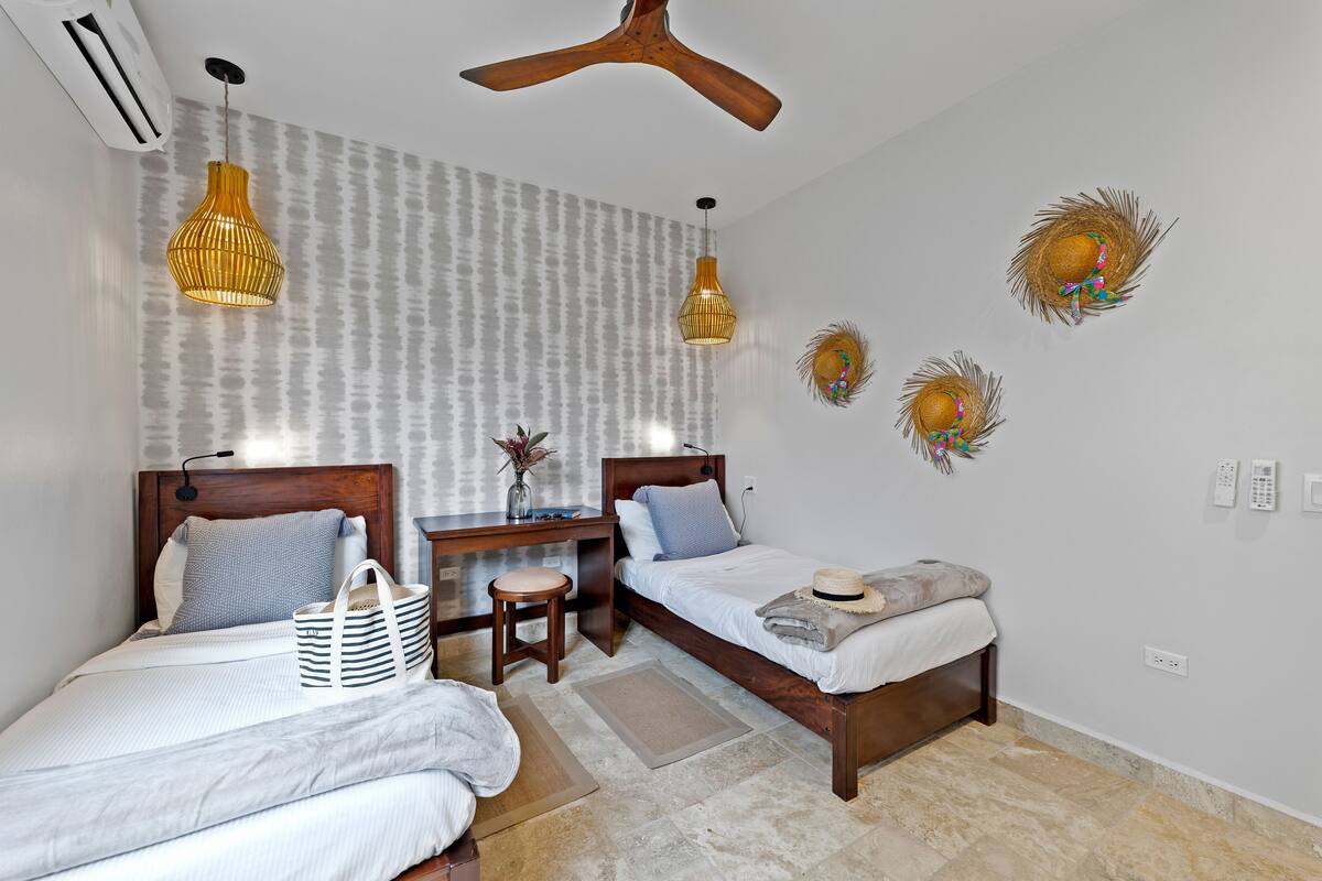 A bedroom with two beds, a desk, and a ceiling fan.