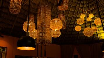 A room with a thatched ceiling and multiple hanging spherical light fixtures.