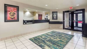 A hotel lobby with a reception desk, framed artwork, a patterned rug, and a glass door entrance. - Extended Stay America Suites Memphis Germantown West (Memphis)