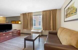 Una sala de estar moderna con una televisión de pantalla plana, un sofá, una mesa de centro y un ventanal con cortinas.