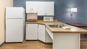 A compact kitchen with white cabinets, a microwave, a sink, and a countertop. - Extended Stay America Suites Memphis Germantown West (Memphis)