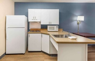 Una cocina compacta con armarios blancos, microondas, fregadero y encimera.