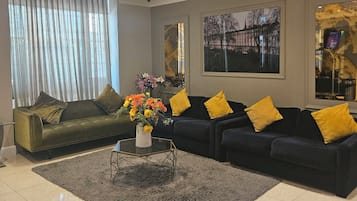Un salon moderne avec un ensemble de canapés, une table basse et une grande fenêtre agrémentée de rideaux.