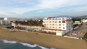 Een hotel aan het strand met meerdere balkons, een zwembad en een ligging direct aan het strand.