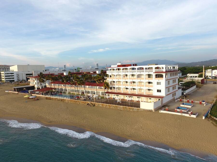 A beachfront hotel with multiple balconies, a pool area, and a beachside location.