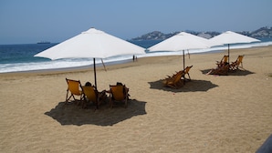 Een strand met zonneschermen en ligbedden.