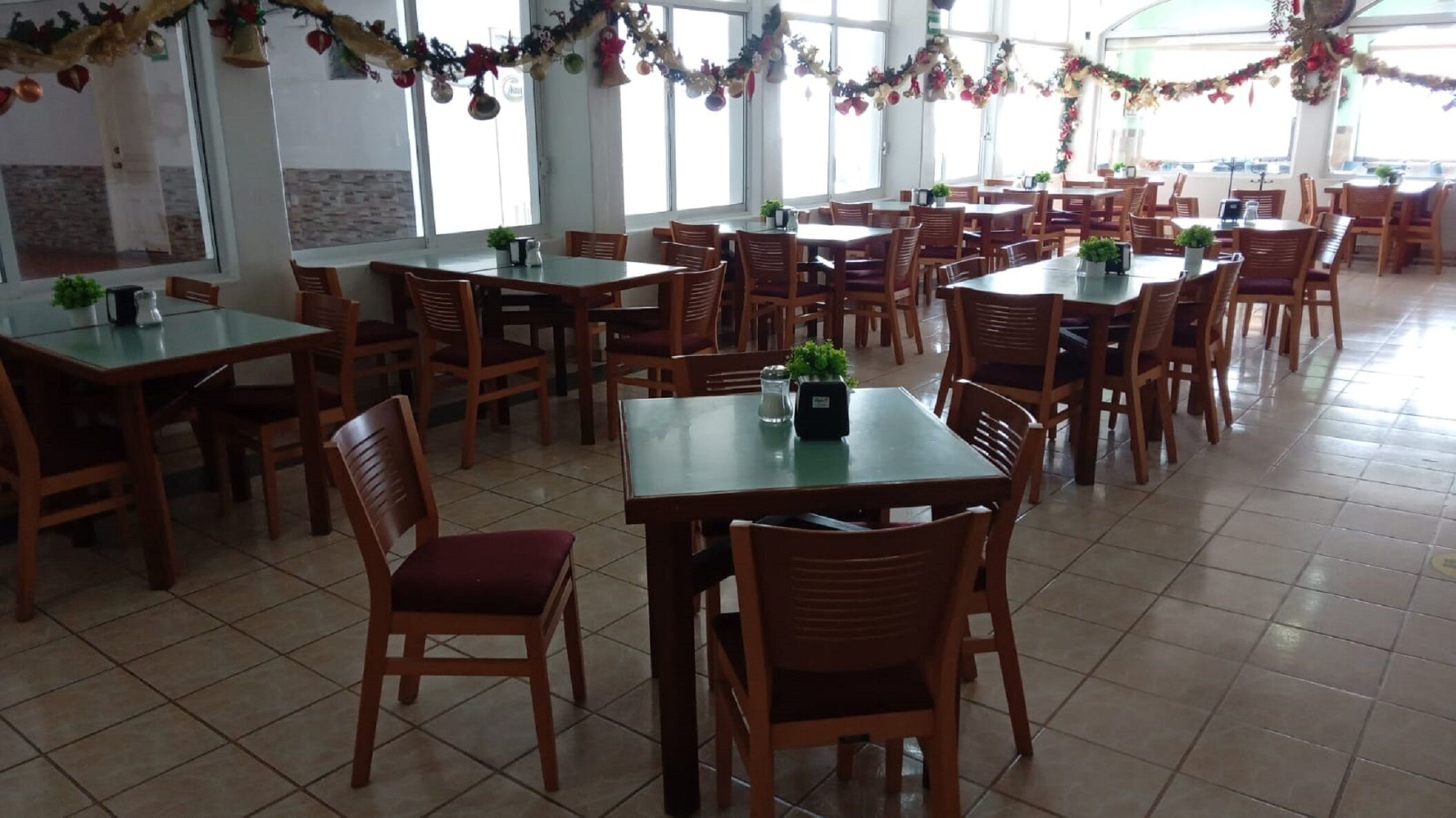 Un vaste espace dédié à la salle à manger, avec de nombreuses tables et chaises, décoré de guirlandes festives.