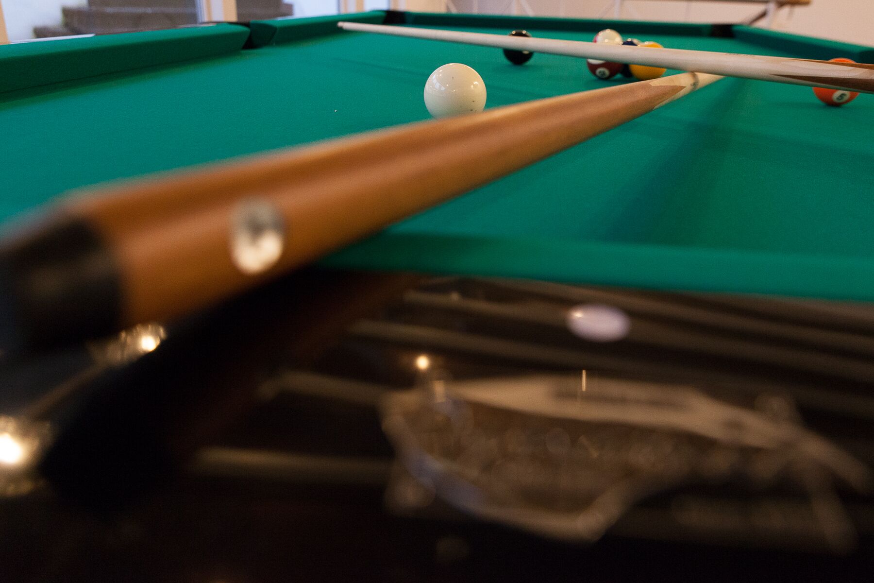 Primer plano de una mesa de billar con una vara y una bola de billar.