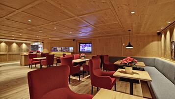 A restaurant with wooden panel walls, red upholstered chairs, and a television screen in the background.
