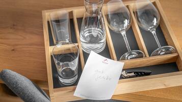 A wooden tray with wine glasses and a bottle, a napkin, and a pen.