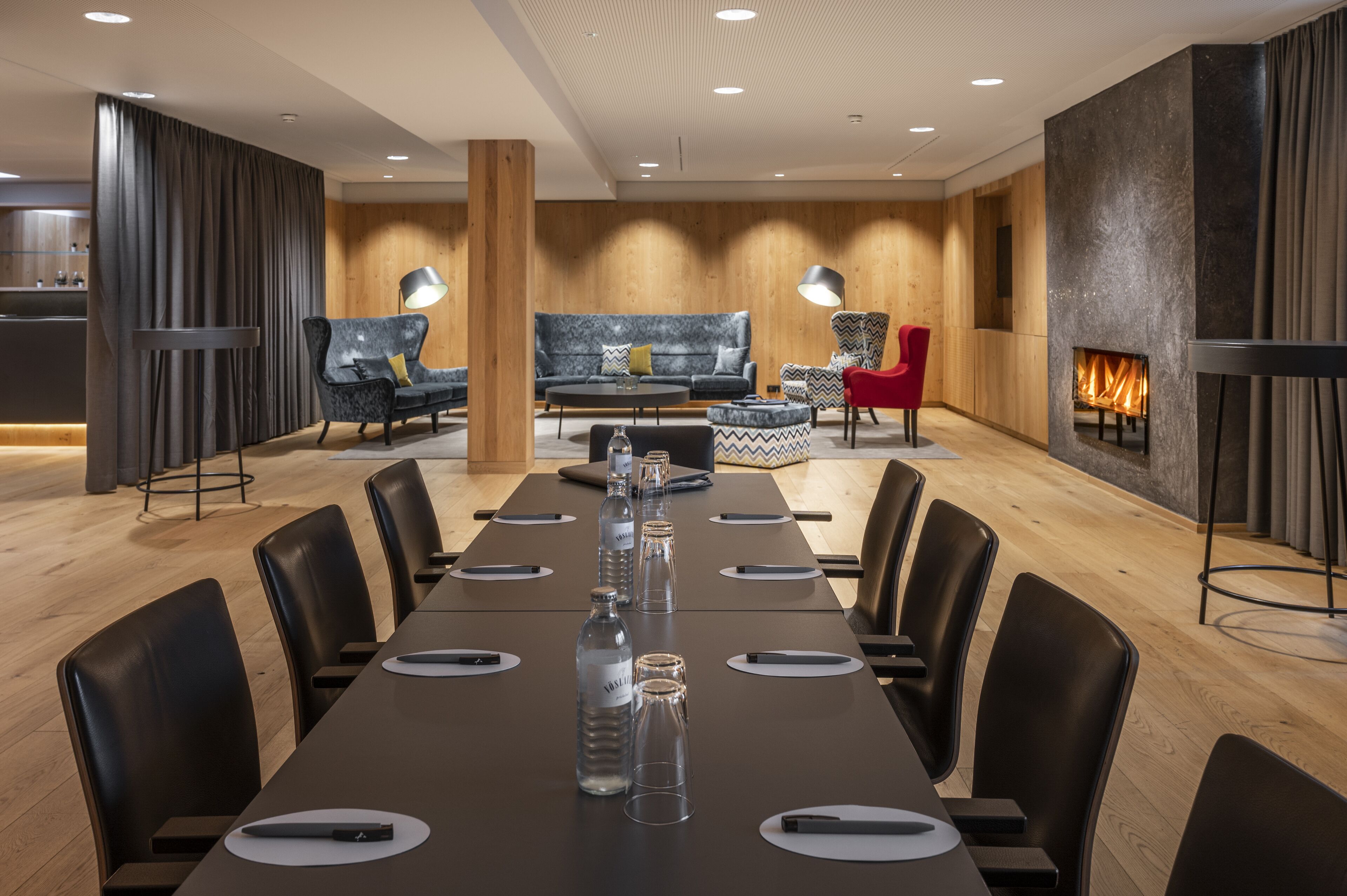 Una sala de conferencias moderna con una mesa larga, sillas negras y una chimenea.