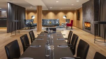 A modern conference room with a long table, black chairs, and a fireplace.