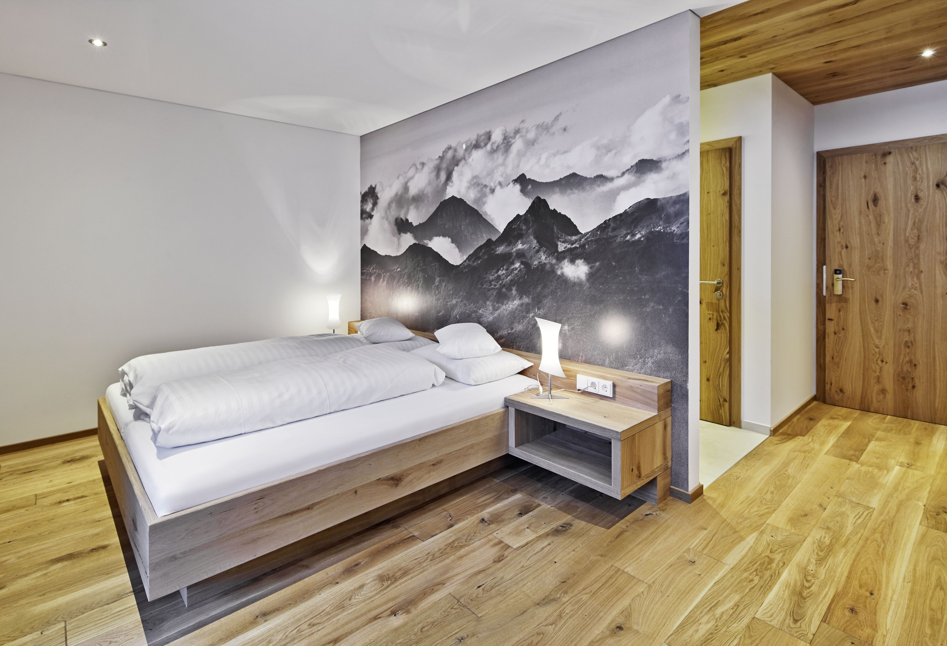 Un dormitorio moderno con una cama de madera, una mesita de noche y una lámpara de pared.