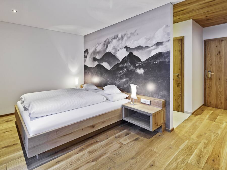 A modern bedroom with a wooden bed, a nightstand, and a wall-mounted lamp.