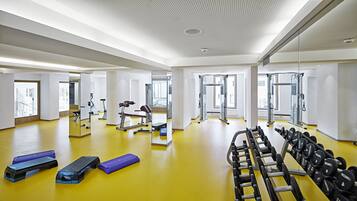 Een moderne sportschool met gele vloer, trainingsapparatuur en grote ramen.