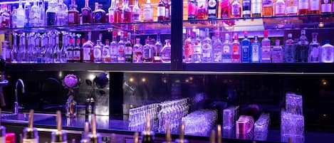 Un bar con estantes llenos de botellas de licores y una variedad de copas.