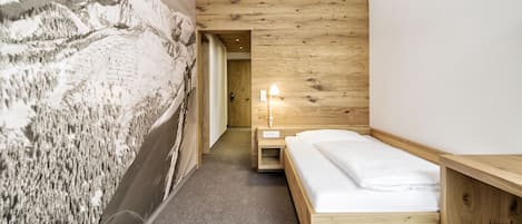 Une chambre à coucher moderne avec un lit en bois, une table de chevet et une fresque murale.