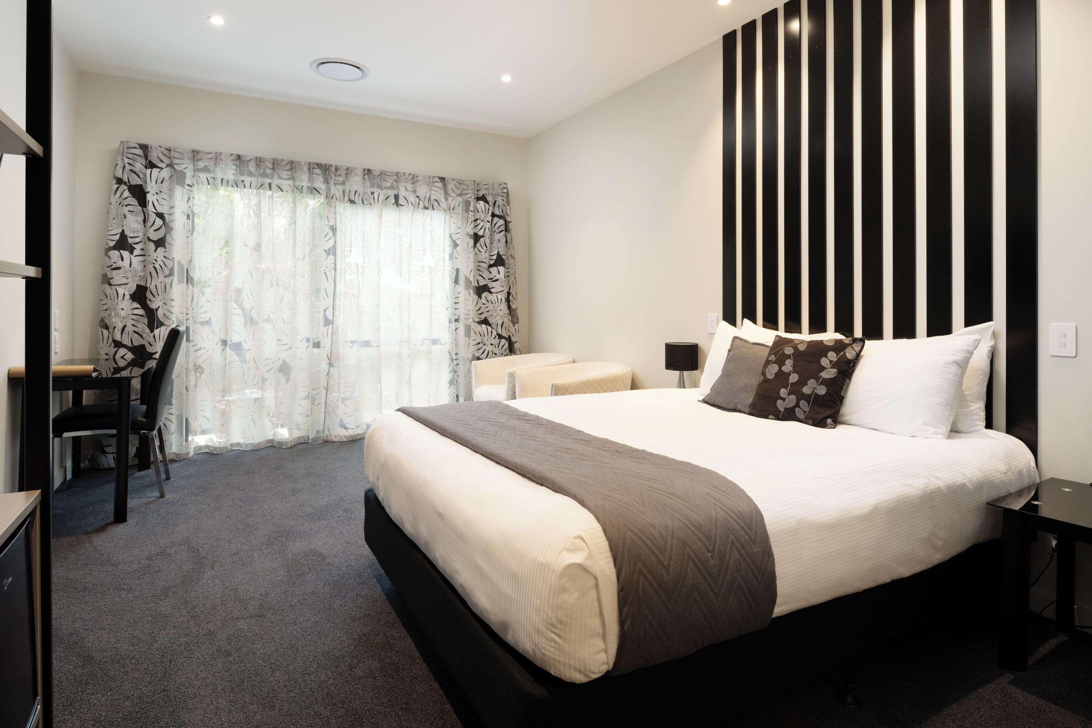 Una habitación de hotel moderna con una cama grande, un escritorio y una silla.