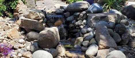Un jardín con una cascada, rocas y una estatua grande.
