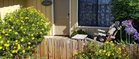 A house with a beige exterior, a wooden fence, and a variety of colorful flowers in the garden.