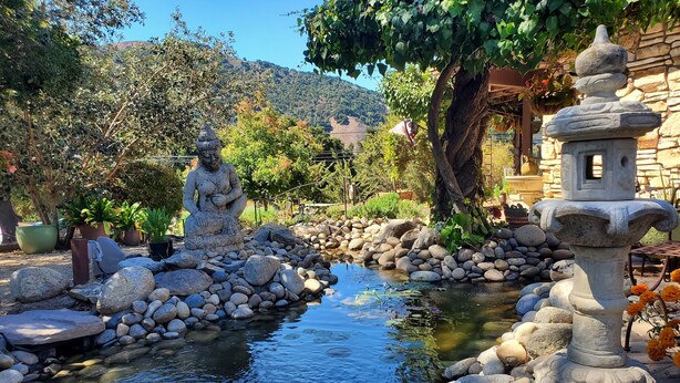 A serene garden with a pond, stone statues, and a stone lantern. - Carmel Valley Lodge and Resort (Carmel Valley)