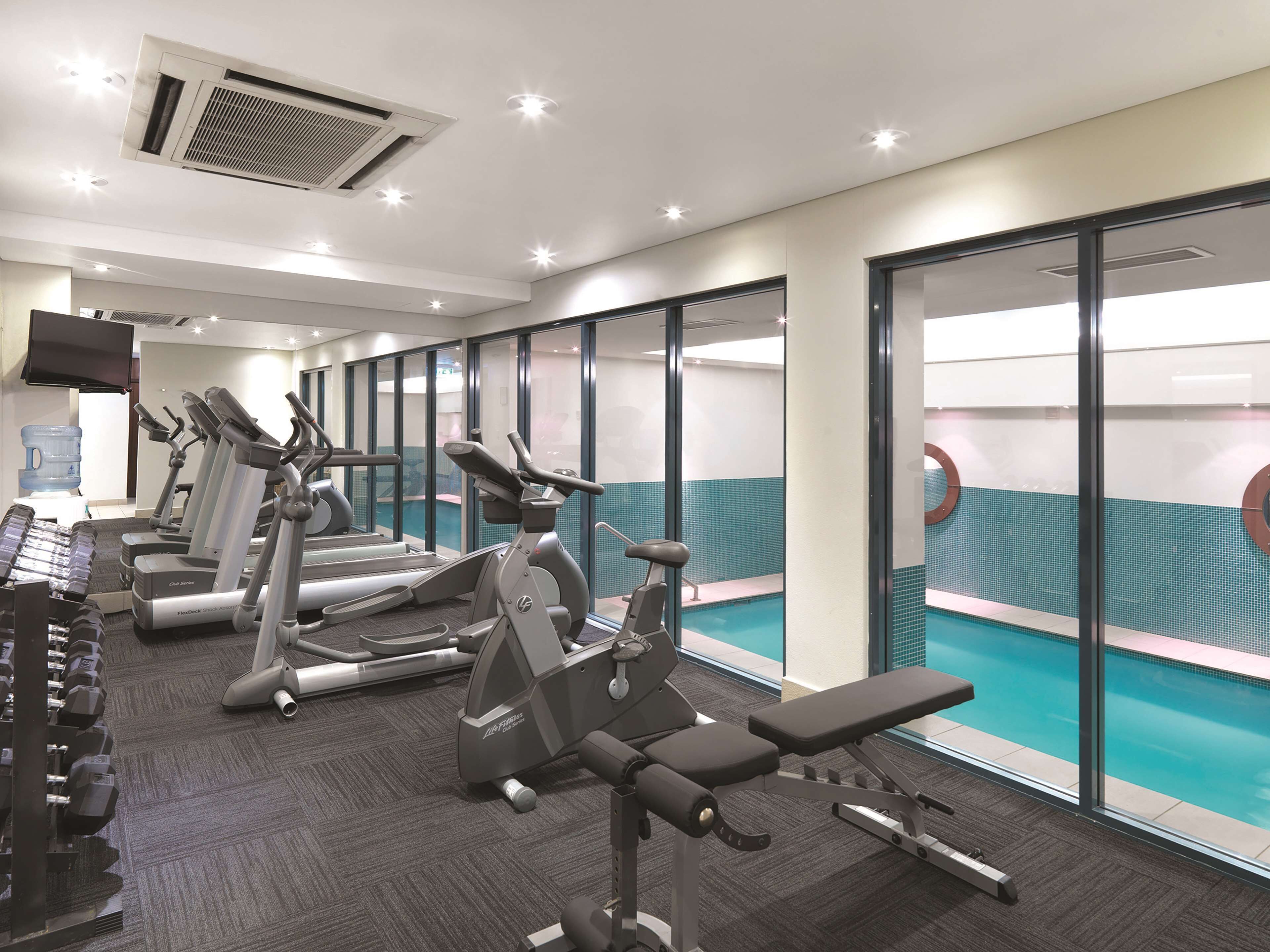 Un gimnasio con cintas de correr, elípticas y bancos de pesas.
